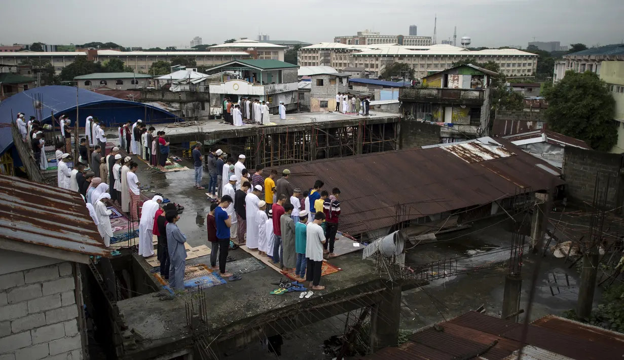 Umat Muslim melaksanakan salat Idul Fitri 1439 H di atap sebuah masjid yang belum selesai di Manila, Filipina (15/6). Umat muslim di seluruh dunia tengah merayakan Hari Raya Idul Fitri 1439 H. (AFP Photo/Noel Celis)