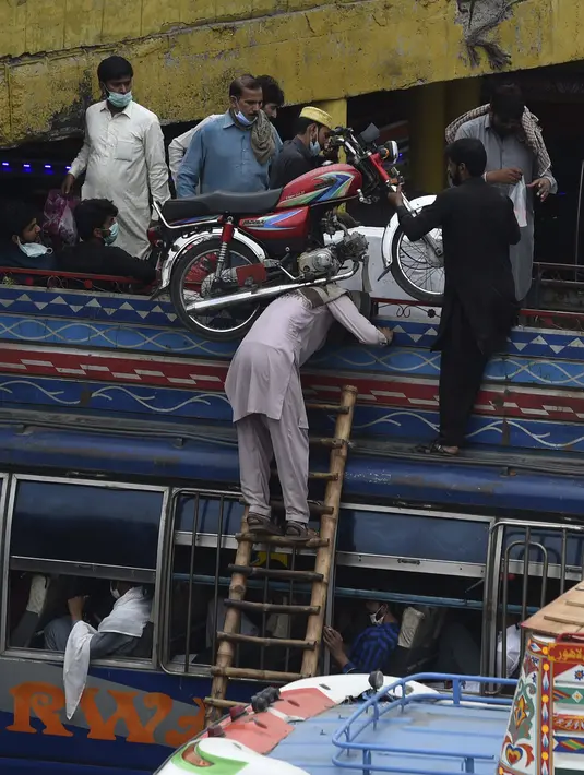 Warga menaiki sepeda motor ke atas bus saat mereka melakukan perjalanan ke kampung halaman mereka menjelang perayaan Idul Fitri di Lahore (7/5/2021). Lebaran Idul Fitri jatuh pada 13 Mei 2021. (AFP Photo/Arif Ali)