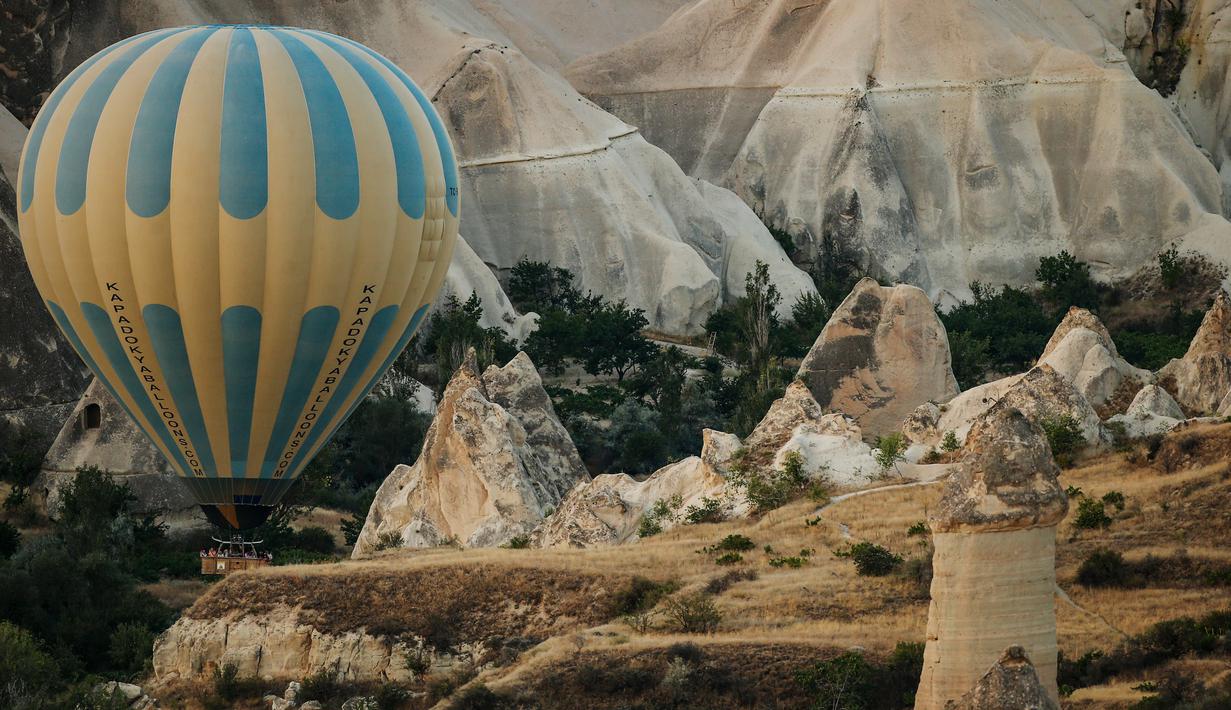Balon udara membawa wisatawan naik ke langit saat matahari terbit di Kapadokia, Turki, Selasa (7/8). Kapadokia memiliki sejumlah keajaiban alam, khususnya Cerobong Peri (Fairy Chimney). (AP Photo/Emrah Gurel)