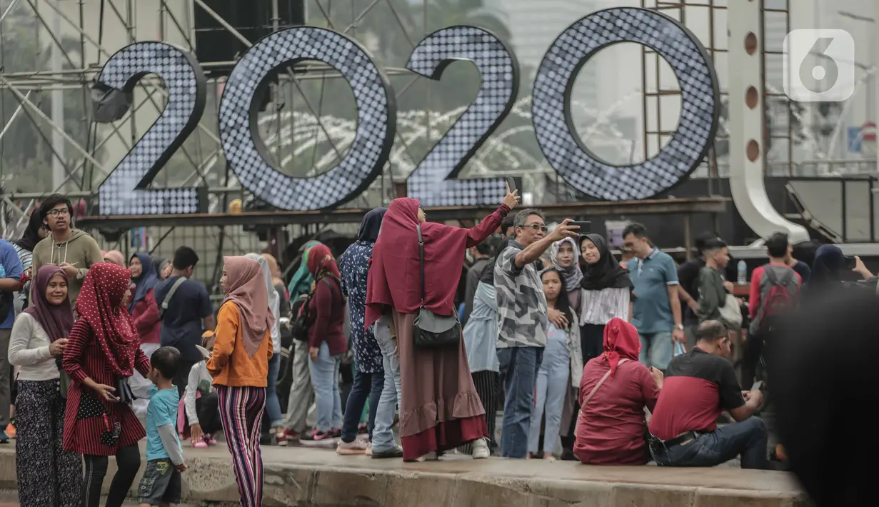 Sejumlah warga berswafoto saat car free day (CFD) di kawasan Bundaran HI, Jakarta, Minggu (29/12/2019). Kendati tidak seramai saat cerah, warga yang berlari, jalan santai, atau swafoto masih menjadi pemandangan di area CFD usai hujan mengguyur Jakarta. (Liputan6.com/Faizal Fanani)