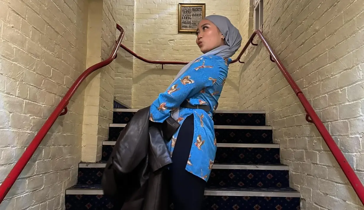 <p>Zara mengenakan celana panjang hitam yang dipadukan dengan baju biru dan jilbab abu-abu saat nonton musikal Aladdin di The Empire Theatre. (Foto: Instagram/ camilliazr)</p>