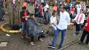 Presiden Joko Widodo melihat warga mengikuti acara cukur rambut massal di Garut, Jawa Barat, Sabtu (19/1). Dalam acara cukur rambut massal ini, rambut Jokowi dicukur oleh tukang cukur langganannya, Herman. (Liputan6.com/Angga Yuniar)