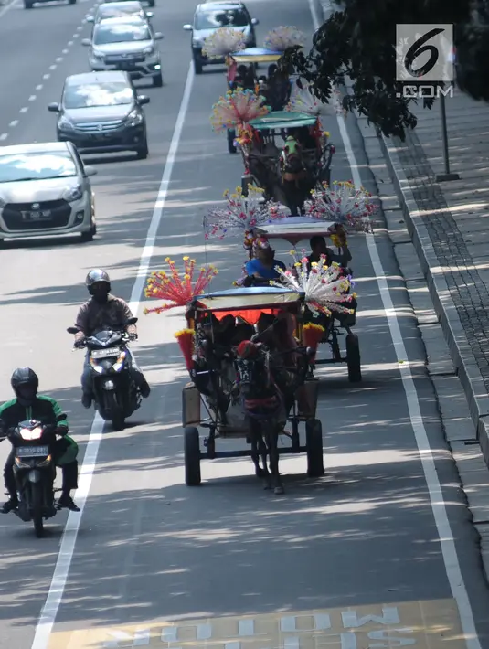 Delman hias membawa penumpang melintasi Jalan Medan Merdeka Barat, Jakarta, Selasa (19/6). Masa libur Lebaran 2018 dimanfaatkan sejumlah warga untuk berwisata di sekitar Monumen Nasional dengan menaiki delman hias. (Liputan6.com/Helmi Fithriansyah)
