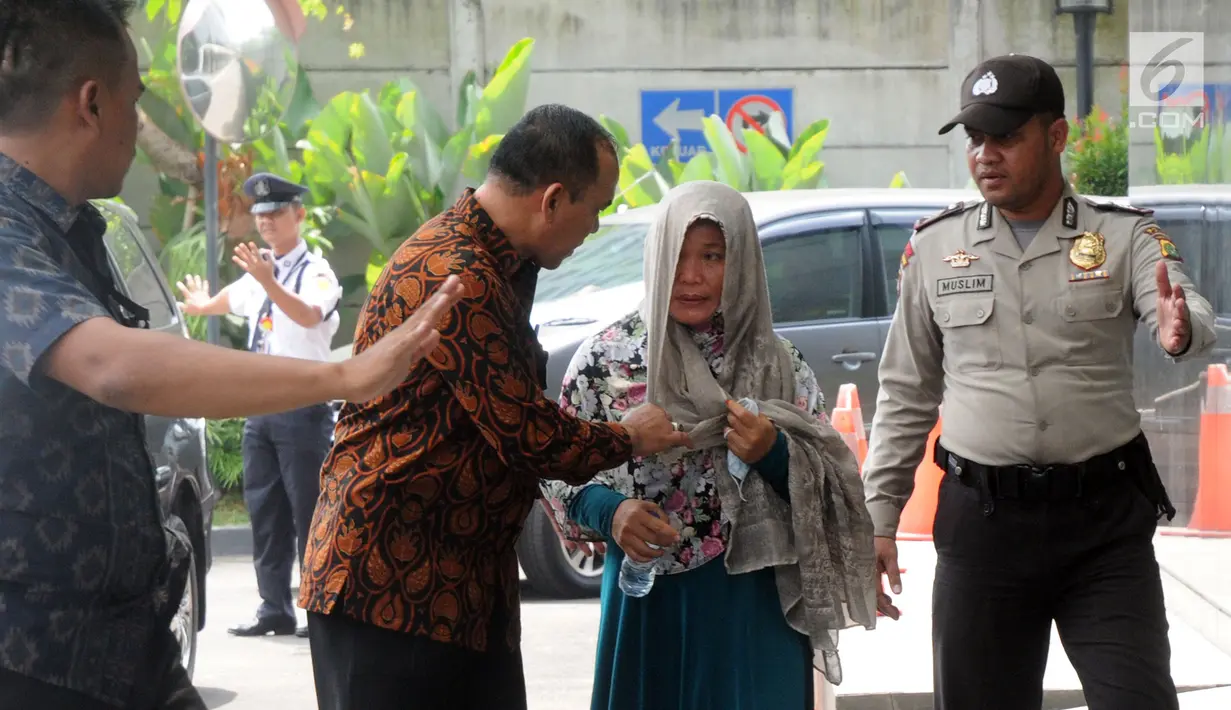 Petugas meminta Kasi Dinkes Bengkulu Selatan Wati membuka kain penutup wajahnya saat tiba di Gedung KPK, Jakarta, Rabu (16/5). KPK juga mengamankan kader Partai Perindo Kabupaten Bengkulu Selatan, Juhari alias Jukak. (Merdeka.com/Dwi Narwoko)