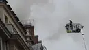 Petugas pemadam berusaha mencapai lantai atas Hotel Ritz yang terbakar, Paris, Selasa (19/1). Api mulai terlihat di lantai tujuh hotel yang telah ditutup sejak Agustus 2012 untuk dilakukan renovasi besar-besaran. (AFP PHOTO/Lionel Bonaventure)