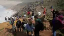 Penonton berkumpul di tebing saat menyaksikan Nazare Tow Surfing Challenge di Praia do Norte atau Pantai Utara, Nazare, Portugal, Selasa (11/2/2020). Hanya peselancar profesional yang boleh bermain ombak di perairan ini. (AP Photo/Armando Franca)