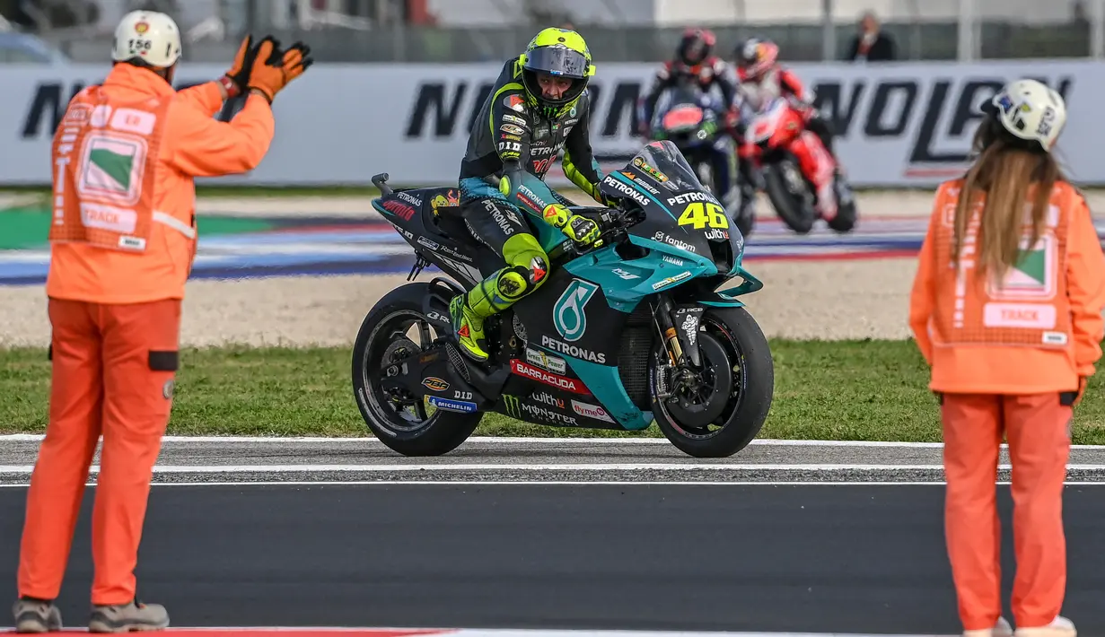Petugas Track marshall (kiri) memberi tepuk tangan kepada Petronas Yamaha SRT, Valentino Rossi setelah balapan MotoGP Emilia Romagna di sirkuit Misano, Minggu (24/10/2021). MotoGP Emila Romagna menjadi balapan terakhir Rossi di tanah kelahirannya, Italia. (ANDREAS SOLARO / AFP)