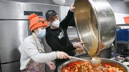Liu (kiri) bersama rekan timnya menyiapkan makanan untuk para petugas medis di Wuhan, Provinsi Hubei, China, Rabu (26/2/2020). Di Wuhan, Liu bersama beberapa koki memasak dan mengantar makanan secara gratis untuk para petugas medis yang berjuang melawan virus corona COVID-19. (Xinhua/Cheng Min)
