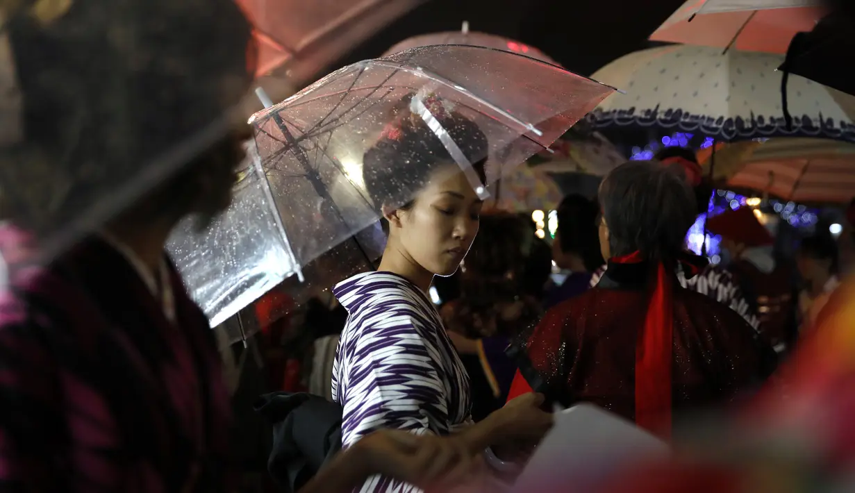 Seorang wanita Jepang mengenakan pakaian tradisional saat berjalan di jalan setelah menghadiri peragaan busana kimono di Oita (18/10/2019). Panjang kimono dibuat hingga ke pergelangan kaki. (AP Photo/Christophe Ena)