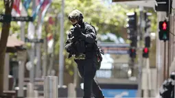 Seorang polisi berlari mengepung situasi kafe Lindt di Sydney, Australia (15/12/2014). Puluhan sandera terperangkap di dalam kafe Lindt di Sydney, Australia. (REUTERS/Jason Reed)