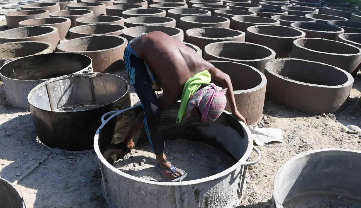 Bocah laki-laki Bangladesh menyelesaikan pembuatan toilet untuk pengungsi Rohingya di Sonarpara, Cox's Bazar, Rabu (11/10). Gelombang besar masuknya pengungsi Rohingya ke Bangladesh menyebabkan melonjaknya permintaan akan toilet. (INDRANIL MUKHERJEE/AFP)
