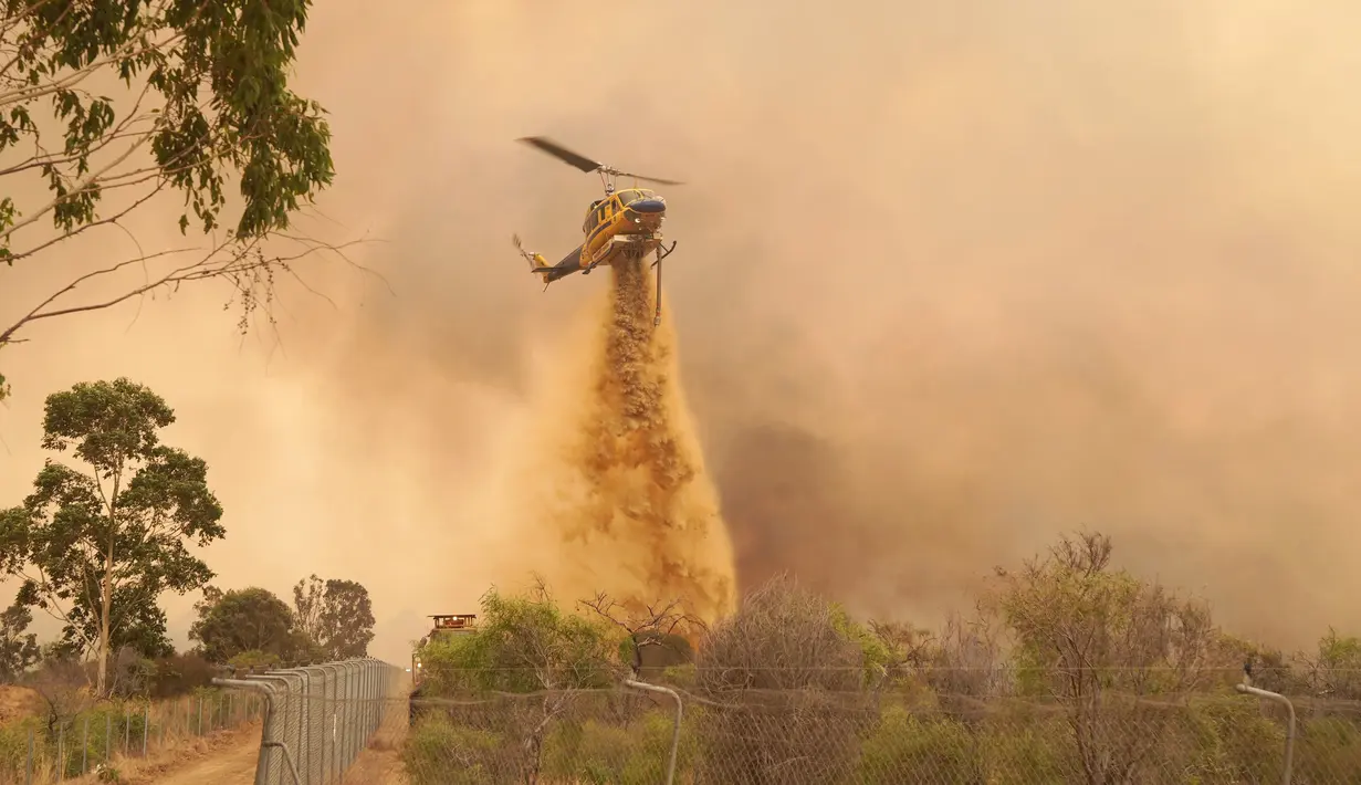 Helikopter menjatuhkan penghambat laju api ke kobaran api dekat Wooroloo, di Perth, Australia, Selasa (2/1/2021). Kebakaran hutan tak terkendali di sebuah wilayah di sebelah timur laut Perth telah menghancurkan puluhan rumah dan kemungkinan mengancam lebih banyak lagi. (Evan Collis/DFES via AP)