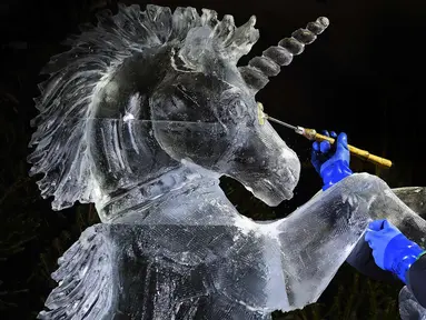 Pemahat es Darren Jackson memberi sentuhan akhir pada patung es Unicorn, sebelum melangsungkan pameran bertema "The Ice Adventure: A Journey Through Frozen Scotland" di Edinburgh, Skotlandia (14/11). (AFP Photo/Andy Buchanan)