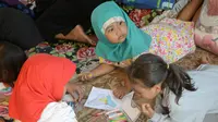 Anak-anak pengungsi korban gempa belajar di tenda pengungsian di Lapangan Tanjung, Lombok Utara, Rabu (8/8). Lebih dari 70.000 orang kehilangan tempat tinggal akibat gempa Lombok berkekuatan 7 SR yang melanda pada Minggu (5/8). (AFP/SONNY TUMBELAKA)