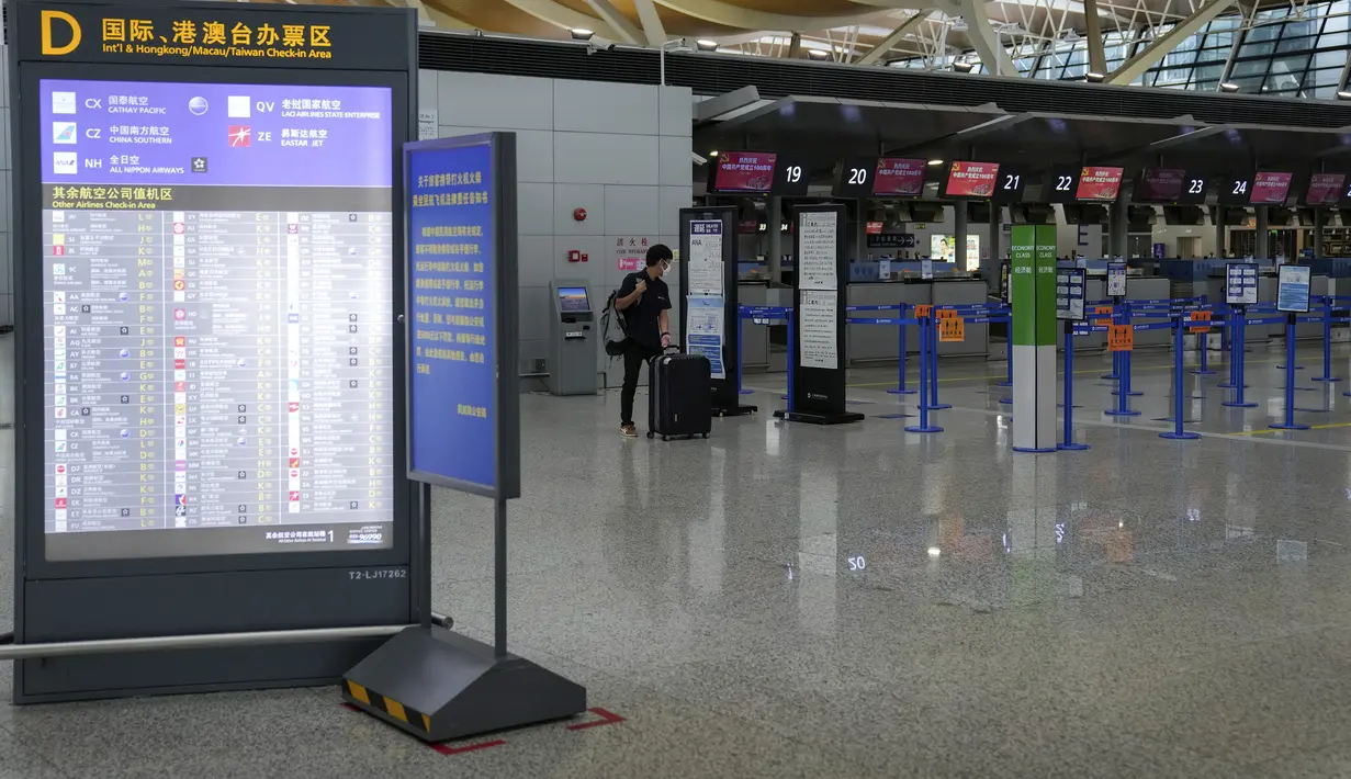 Penumpang melihat pemberitahuan informasi penerbangan setelah semua penerbangan dibatalkan di Bandara Internasional Pudong, Shanghai, Minggu (25/7/2021). China menutup jalur kereta api dan pelabuhan, serta membatalkan jadwal penerbangan sebelum topan In-Fa diperkirakan mendarat (AP Photo/Andy Wong)