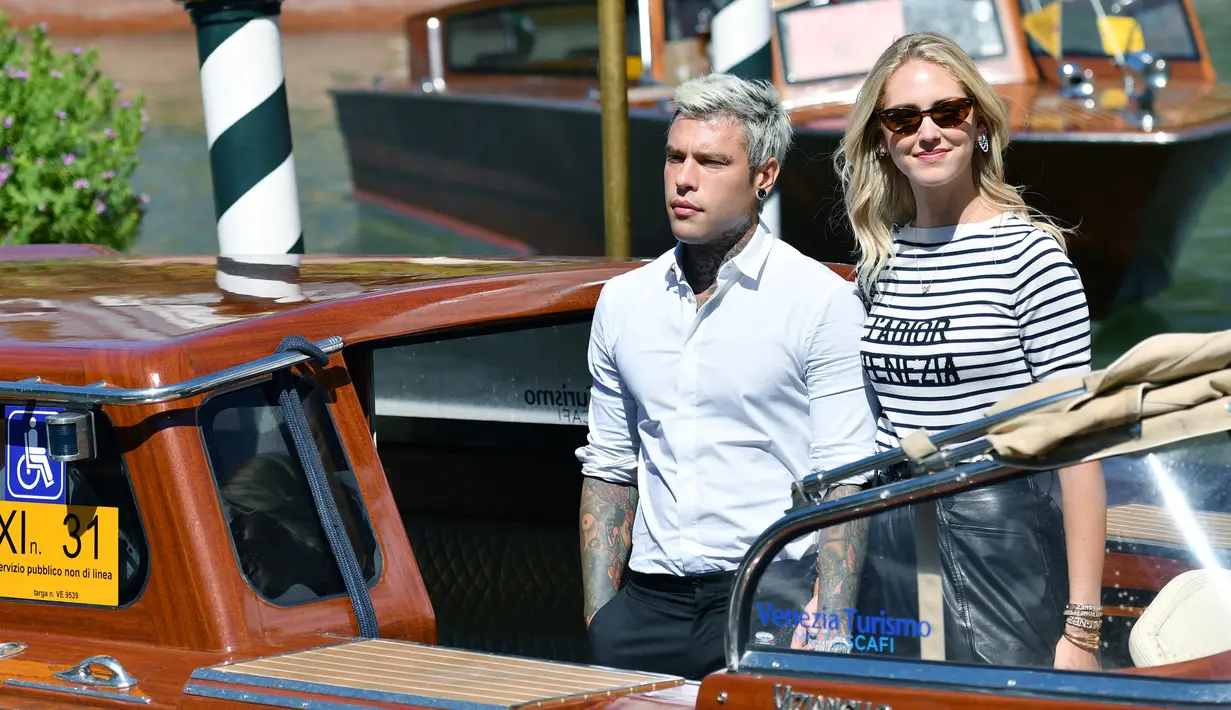 Blogger sekaligus perancang busana Chiara Ferragni (kanan) bersama suaminya rapper Federico Leonardo Lucia atau Fedez saat tiba untuk menghadiri Venice Film Festival 2019 di Dermaga Hotel Excelsior, Venesia, Italia, Selasa (3/9/2019). (Alberto PIZZOLI/AFP)