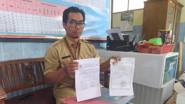 Nur Khabib selaku Kepala Sekolah SDN Ploso 4 Kudus menunjukkan berkas surat pendaftaran kepindahan atas nama Ajib.(Liputan6.com/Arief Pramono)
