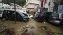 Mobil-mobil yang rusak terlihat di jalan yang banjir setelah hujan deras memicu tanah longsor yang meruntuhkan bangunan dan menyebabkan 12 orang hilang, di Casamicciola, di pulau Ischia, Italia selatan, Sabtu, 26 November 2022. (AP Photo/Salvatore Laporta)