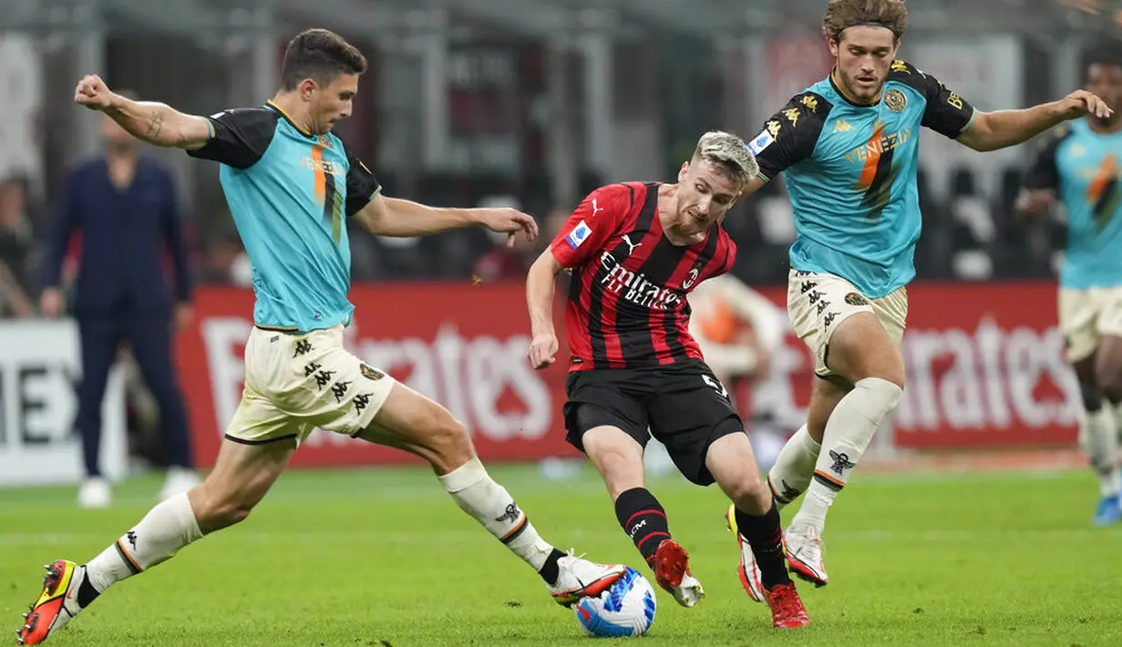 Gelandang AC Milan, Alexis Saelemaekers berebut bola dengan bek Venezia, Mattia Caldara pada laga pekan ke-5 Serie A 2021/22 di San Siro, Kamis (23/9/2021) dini hari WIB. AC Milan Milan menaklukkan tamunya Venezia 2-0. (AP Photo/Antonio Calanni)