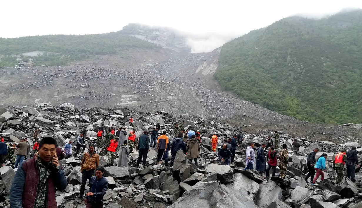 Petugas dan warga mencari korban di antara puing bebatuan usai longsor menerjang di Desa Xinmo, Sichuan, China, Sabtu (24/6). Sekitar 100 orang hilang diduga tertimbun bebatuan akibat longsor dan sekitar 40 rumah warga hancur. (AFP Photo/Str/China Out)