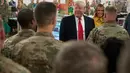 Presiden Donald Trump dan ibu negara Melania Trump mengunjungi pasukan militer Amerika di Pangkalan Udara al Asad, Irak, Rabu (26/12). Trump memberikan kejutan dengan melakukan kunjungan mendadak tersebut dalam rangka perayaan Natal. (AP/Andrew Harnik)