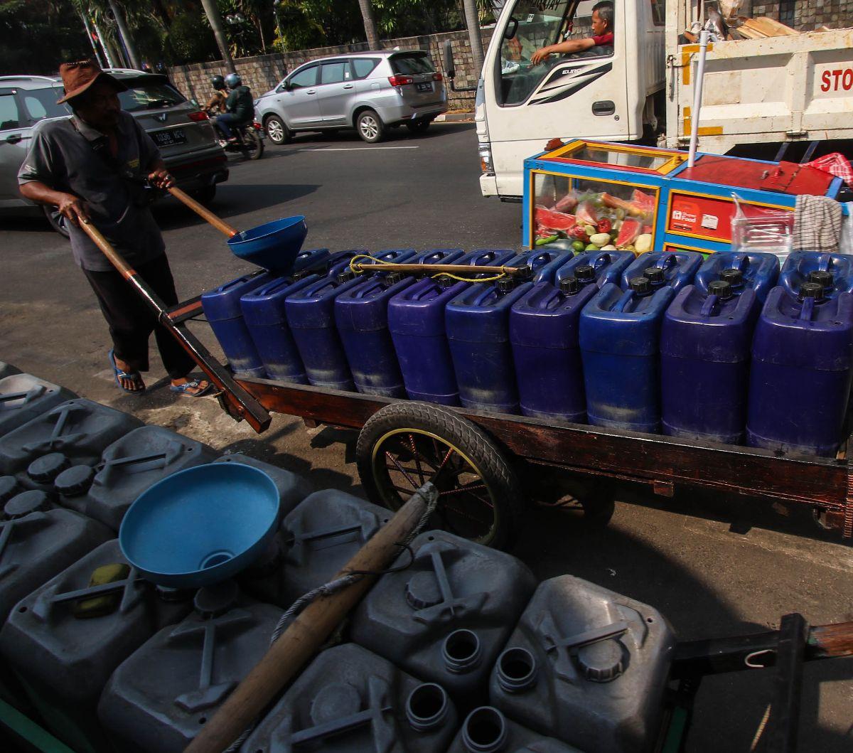 Pedagang mengisi air bersih ke dalam jeriken saat disiapkan untuk dijual keliling dengan gerobak dorong di kawasan Jakarta Barat, Senin (18/9/2023).