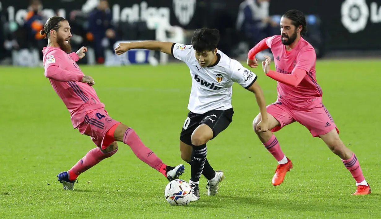 Pemain Valencia, Lee Kang-in, berusaha melewati pemain Real Madrid pada laga Liga Spanyol di Stadion Mestalla, Minggu (8/11/2020). Valencia menang dengan skor 4-1. (AP/Alberto Saiz)