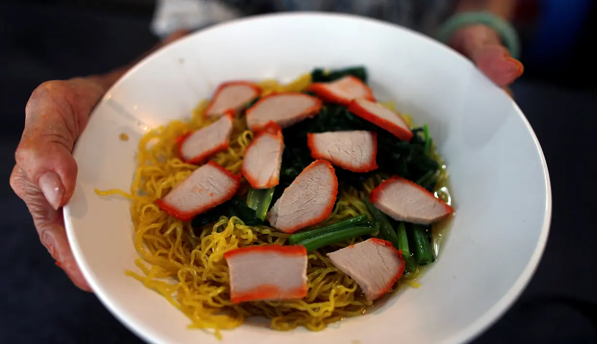 Nenek Leong Yuet Meng memperlihatkan semangkuk mie pangsit buatannya di warungnya di Singapura (22/3). Nenek Leong memulai aktivitasnya di dapur dari jam 8 pagi sampai jam 5 sore. (Reuters/Edgar Su)