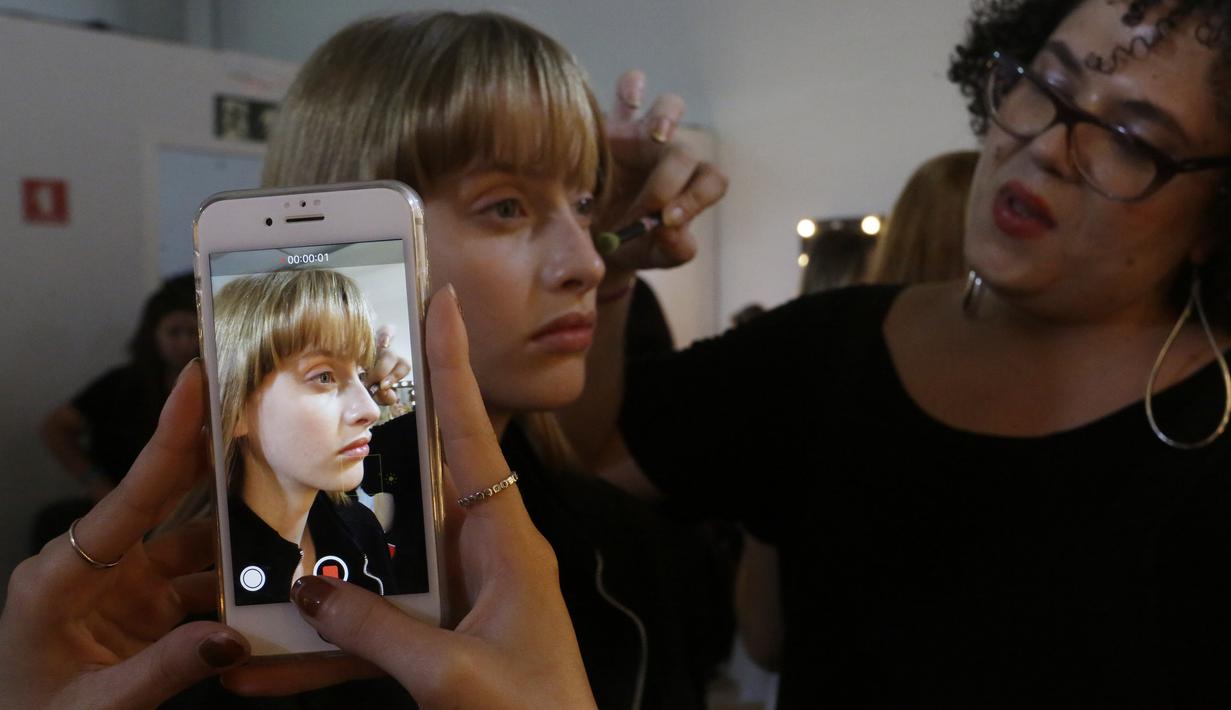 Model saat dirias wajahnya di belakang panggung sebelum tampil membawakan busana koleksi Beira selama Sao Paulo Fashion Week di Sao Paulo, Brasil (16/10/2019). SPFW ke-48 akan berlangsung hingga 18 Oktober.  (AP Photo / Nelson Antoine)