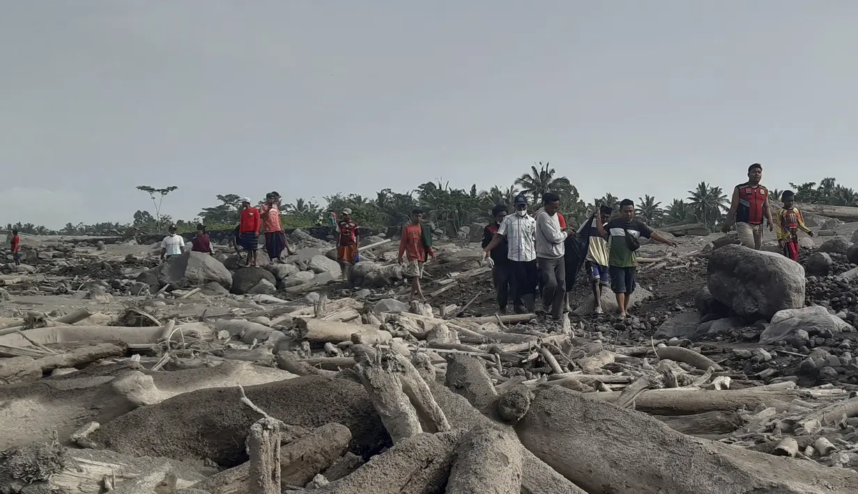 Tim penyelamat dan warga membawa kantong jenazah berisi jenazah korban letusan Gunung Semeru, di Desa Candi Puro, Lumajang, Jawa Timur, Selasa (7/12/2021). (AP Photo/Rokhmad)