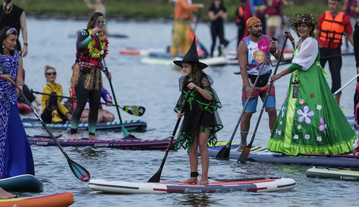 Orang-orang berdiri di atas papan SUP selama festival dayung berdiri (stand up paddle) di kanal dayung Olimpiade Krylatskoye, Moskow, Rusia, Minggu (12/9/2021). Festival dihadiri para peserta dalam balutan kostum warna-warni yang menggambarkan aneka karakter dalam tokoh film. (AP/Pavel Golovkin)