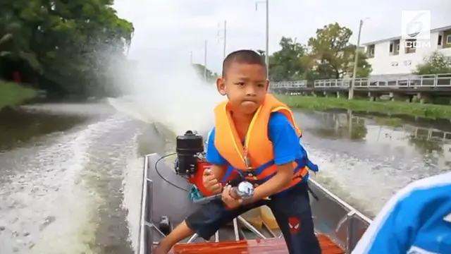 Bocah berusia 5 tahun mengemudikan motor boat ke sekolah. Motor boat menjadi alat transportasi utama di tempat tinggalnya di pinggiran Bangkok.