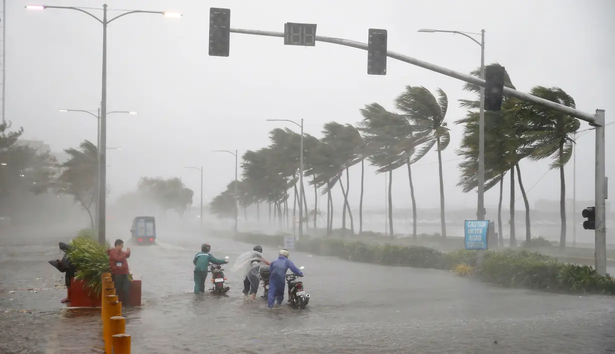 Pengendara motor menerjang hujan dan angin kencang yang dibawa Topan Mangkhut di Manila, Filipina (15/9). Topan Mangkhut menghantam pantai timur laut Filipina pada Sabtu pagi menghancurkan sebagian wilayah di negara tersebut. (AP Photo/Bullit Marquez)