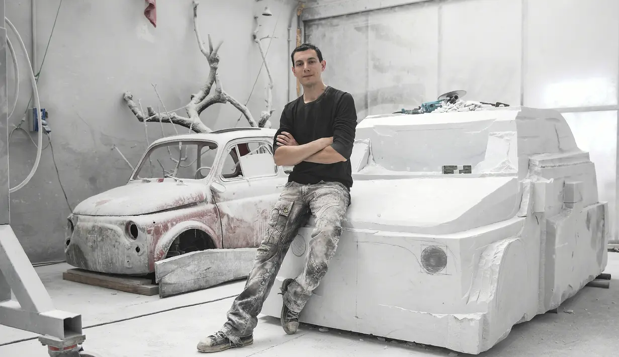 Seniman Italia, Nazareno Biondo berpose dengan replika mobil Fiat 500 berbahan dasar marmer Carrara pahatannya di Cafasse, dekat Turin, Italia, Rabu (16/5). (MARCO BERTORELLO/AFP)