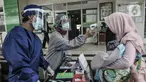 Petugas paramedis memeriksa suhu tubuh seorang ibu sebelum mengantarkan anaknya mengikuti imunisasi di Puskesmas Kecamatan Jatinegara, Jakarta, Kamis (26/11/2020). (merdeka.com/Iqbal S. Nugroho)