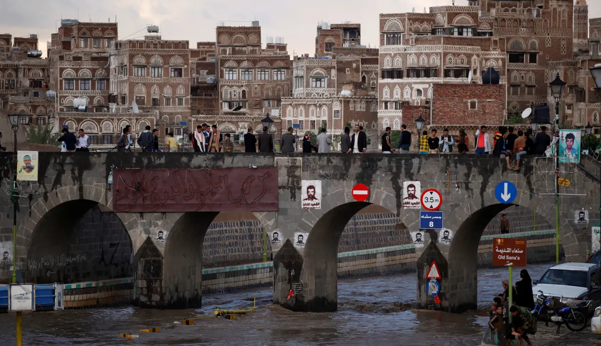 Sejumlah warga melihat jalanan yang terendam banjir di atas jembatan di Sanaa, Yaman, Selasa (2/8). Hujan lebat yang mengguyur Sanaa membuat salah satu ruas jalan di kota itu berubah seakan menjadi sungai. (REUTERS / Khaled Abdullah)
