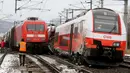 Regu penyelamat berdiri dekat dua rangkaian kereta penumpang yang terlibat tabrakan dekat stasiun di Niklasdorf, Austria, Senin (12/2). Pihak berwenang masih melakukan penyelidikan untuk mengetahui penyebab pasti kecelakaan tersebut. (AP/Ronald Zak)