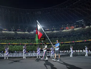 Seorang relawan membawa bendera nasional Afghanistan dalam defile upacara pembukaan Paralimpiade Tokyo 2020 di Tokyo, Selasa (24/8/2021). Bendera Afghanistan dikibarkan tanpa kehadiran satu pun atletnya menyusul kondisi negaranya pasca dikuasai oleh Taliban. (Joel Marklund for OIS via AP)