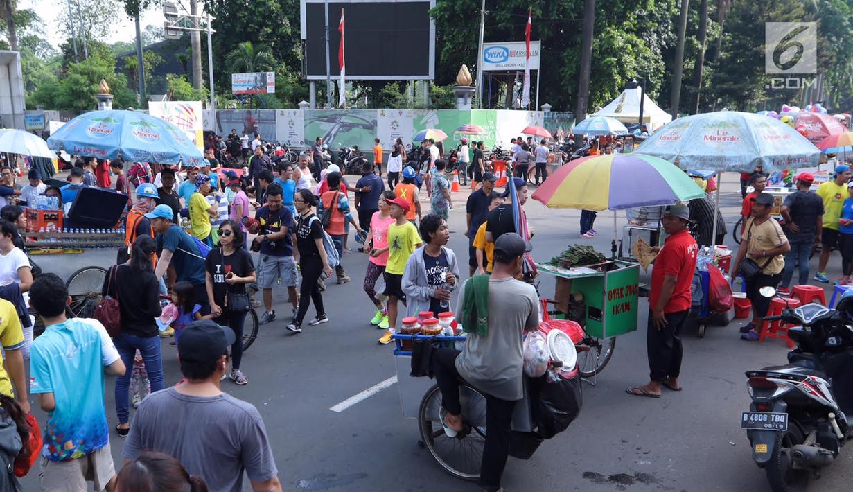 Penjaja makanan melintas saat pelaksanaan Car Free Day di kawasan Senayan, Jakarta, Minggu (8/10). Tidak adanya sekat dengan PKL, mengakibatkan aktivitas pengunjung yang ingin berolahraga kurang leluasa. (Liputan6.com/Fery Pradolo)