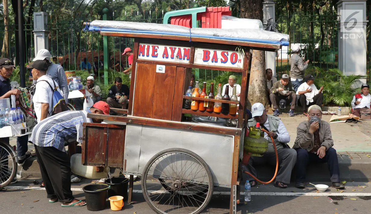 Pedagang asongan melayani pembeli yang mayoritas massa yang melakukan aksi di sekitaran Jalan Medan Merdeka Barat, Jakarta, Kamis (27/6/2019). Massa yang melakukan aksi terkait sidang putusan perselisihan hasil Pilpres 2019 memberi keuntungan bagi para pedagang. (Liputan6.com/Helmi Fithriansyah)