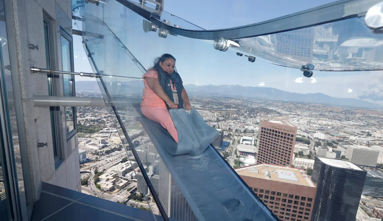 Seorang wanita mencoba berseluncur menggunakan skyslide di lantai 69 dan 70 dari Bank Tower AS, Los Angeles , California, (20/6). OUE Skyspace LA adalah tempat paling tinggi di California. (REUTERS / Lucy Nicholson)
