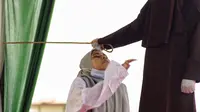 Seorang wanita bereaksi saat dia dicambuk di depan umum oleh anggota polisi Syariah di Lhokseumawe, Aceh, Senin (28/6/2021). Wanita yang didakwa telah melakukan hubungan seks pranikah itu dihukum dengan 100 cambukan. (Azwar Ipank/AFP)