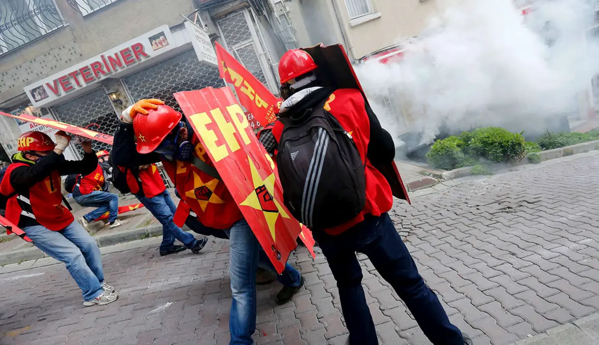 Massa buruh yang mencoba masuk ke Taksim Square (pusat kota Istanbul), Turki (1/5/2014) dicegah pihak kepolisian. Tampak, beberapa pengunjuk rasa melindungi diri dari gas air mata yang ditembakkan oleh polisi anti huru hara. (REUTERS/Murad Sezer)