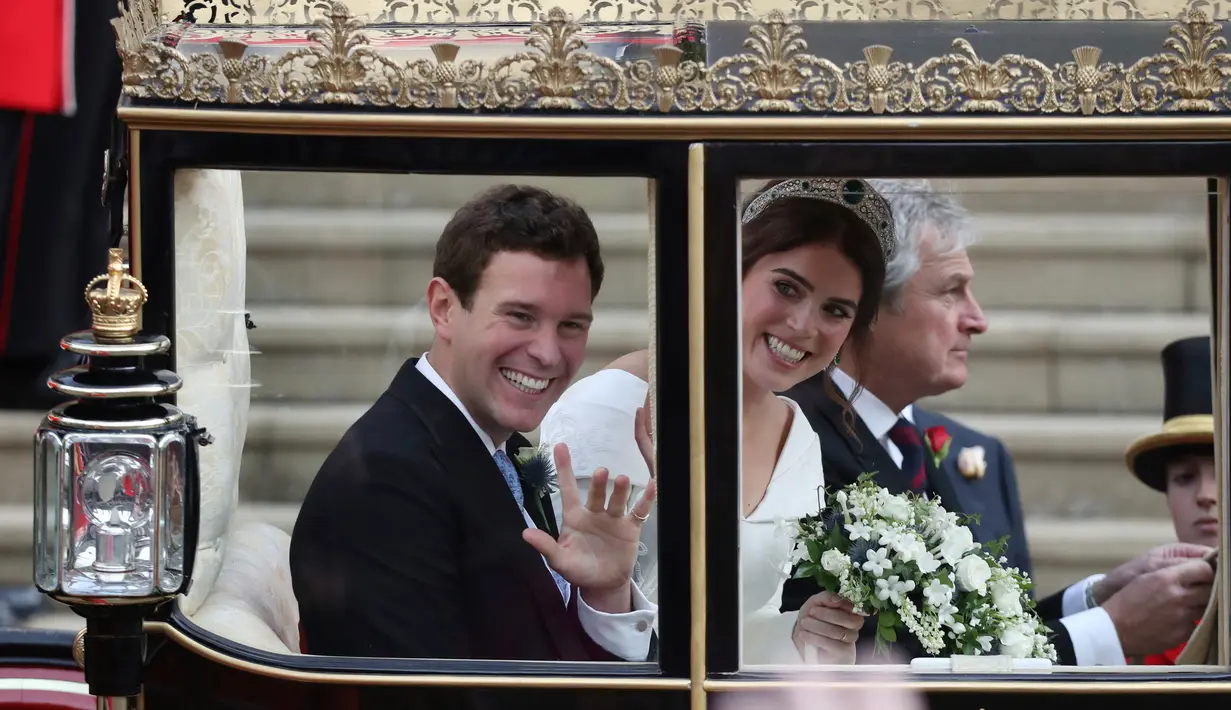 Putri Eugenie dan Jack Brooksbank menyapa mesyarakat saat menaiki kereta kencana usai melangsungkan pernikahan di Kapel St. George, Windsor Castle, London, Inggris,  Jumat (12/10). (Andrew Matthews, Pool via AP)
