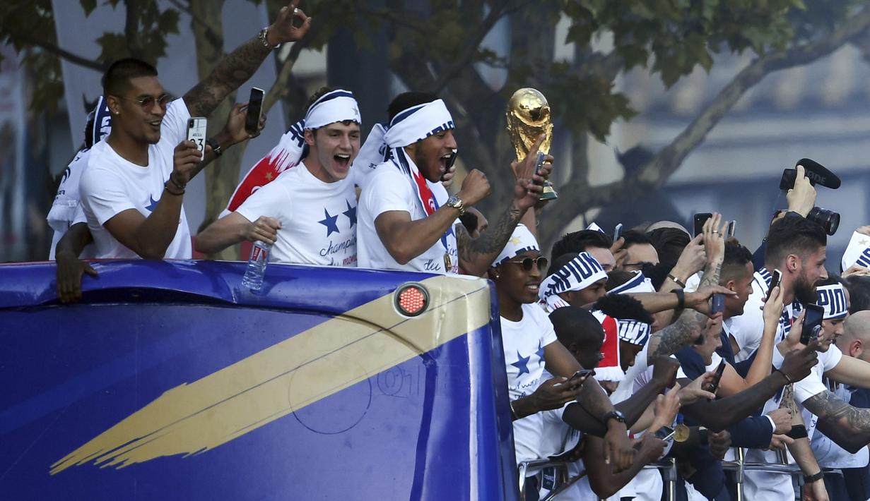 Pemain Prancis membawa trofi Piala Dunia serta mengabadikan momen bahagia bersama fans di Champs-Elysee avenue, Paris, (16/7/2018). Prancis berpesta merayakan keberhasilan Les Bleus meraih trofi Piala Dunia 2018. (Eric Feferberg/Pool Photo via AP)