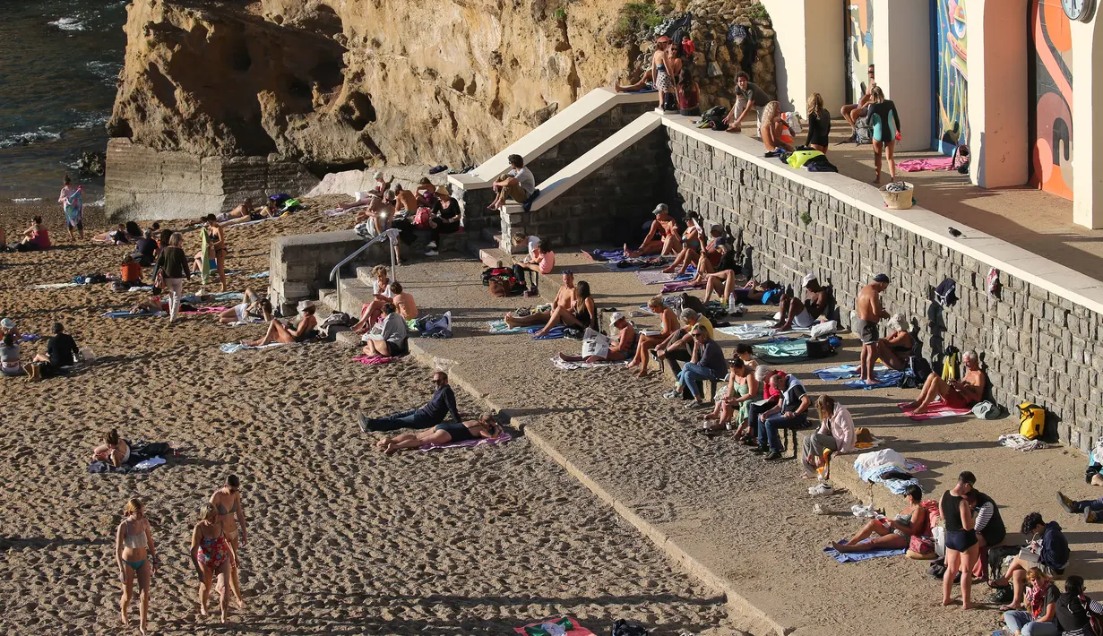 Orang-orang berjemur di pantai Biarritz, barat daya Prancis, Rabu (27/10/2021). Suhu di Prancis barat daya mencapai 20 derajat Celcius (68 Fahrenheit). (AP Photo/Bob Edme)