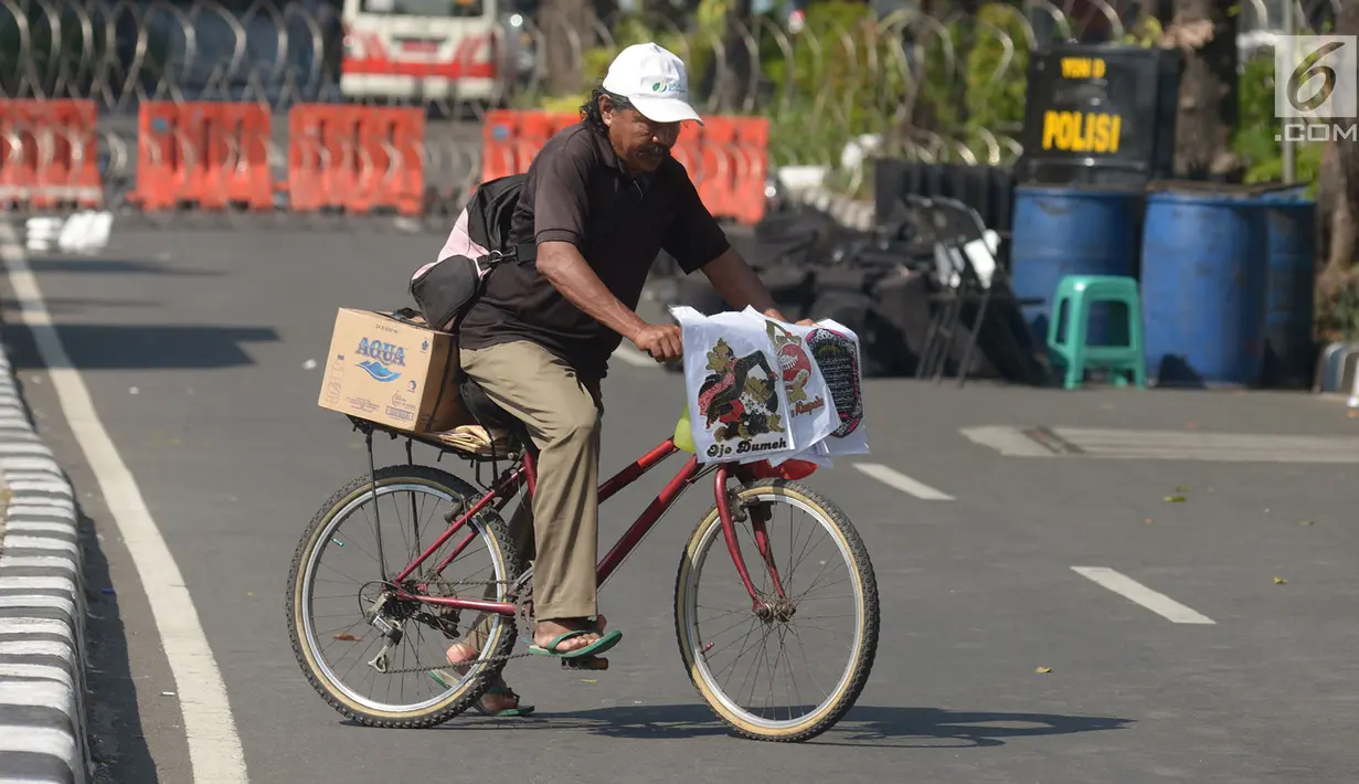 Seorang pedagang melintas dekat jalan yang ditutup menuju Gedung Mahkamah Konstitusi (MK) di Jakarta, Kamis (27/6/2019). Rekayasa lalu lintas sudah disiapkan di sekitar gedung MK selama pelaksanaan sidang pembacaan putusan hasil sengketa pilpres 2019. (merdeka.com/Imam Buhori)