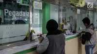 Petugas melayani warga saat transaksi di pegadaian di Jakarta, Kamis (15/6). Meningkatnya kebutuhan masyarakat jelang Lebaran membuat banyak orang menggadaikan barang berharga guna memenuhi kebutuhan yang mendesak. (Liputan6.com/Faizal Fanani)