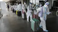 Penumpang asing yang mengenakan pakaian pelindung berjalan untuk penerbangan mereka ke China di Bandara Internasional Manila, Filipina, Senin (18/1/2021). Infeksi virus corona COVID-19 di Filipina telah melonjak melewati 500 ribu kasus.  (AP Photo/Aaron Favila)