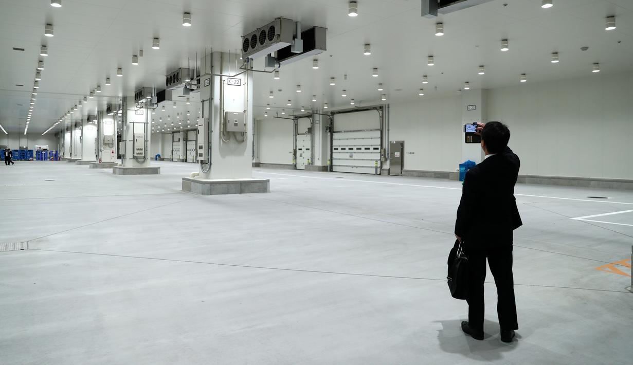 Seorang pria mengambil gambar pasar ikan Toyosu sebelum upacara pembukaan di Tokyo, Kamis (13/9). Pemerintah kota akan merelokasi pasar ikan Tsukiji yang terkenal di Tokyo dan merupakan pasar ikan terbesar di dunia, ke lokasi ini. (AFP/Behrouz MEHRI)